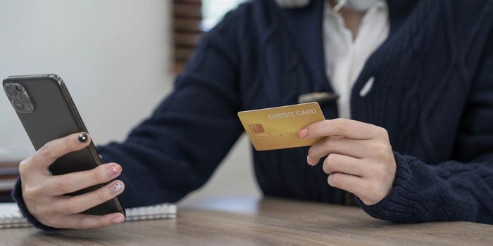 Close-up hand woman using smart phone, tablet payments and holding credit card online shopping, omni channel, digital tablet docking keyboard computer at home.