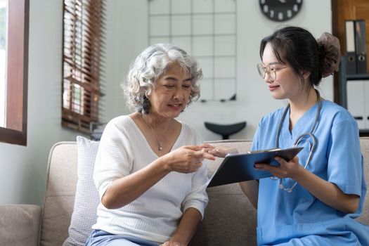 Asian senior woman patient on sofa talking with friendly nurse. healthcare concept.