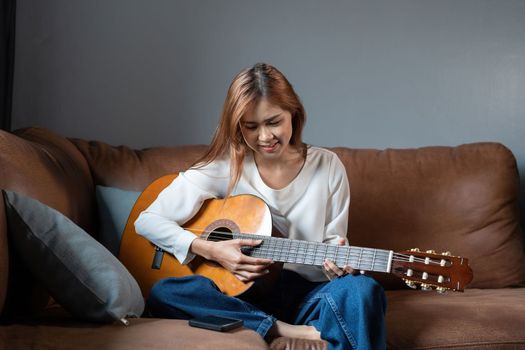 Image of happy beautiful woman playing guitar and composing song