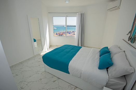 Interior design decor furnishing of luxury show home bedroom showing furniture and double bed in resort with sea view from window