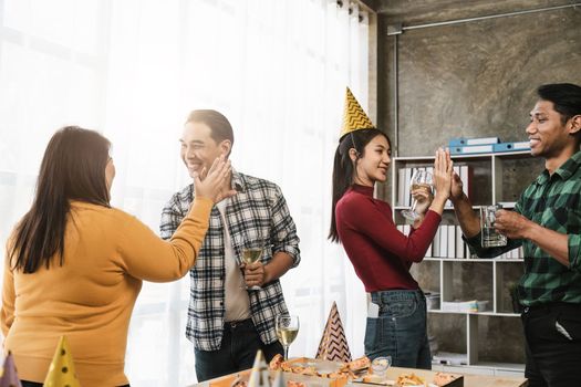 Group of happy colleagues having fun at a new year celebration or business success. Coworkers with diverse people at the office party.