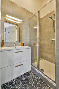 Glass partition between shower tap and wall hung toilet in modern restroom at home