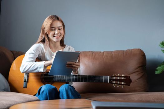 Image of happy beautiful woman playing guitar and composing song.