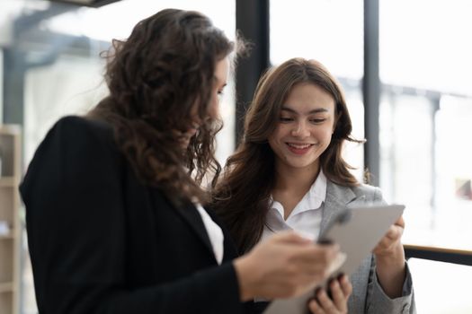 Diverse businesspeople cooperate work together discussing company financial statistics, multiracial colleagues collaborate brainstorm with finance on tablet
