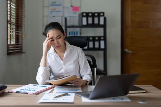 Tired asian business woman with headache at office, feeling sick at work.