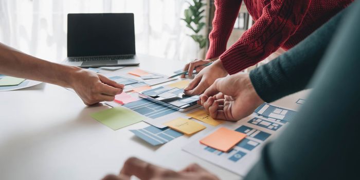 ux developer and ui designer brainstorming about mobile app interface wireframe design on table with customer breif and color code at modern office