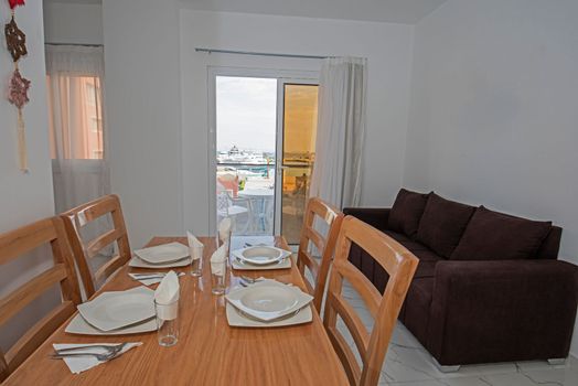 Living room lounge area in luxury apartment show home showing interior design decor furnishing with open plan dining area and sea view from balcony