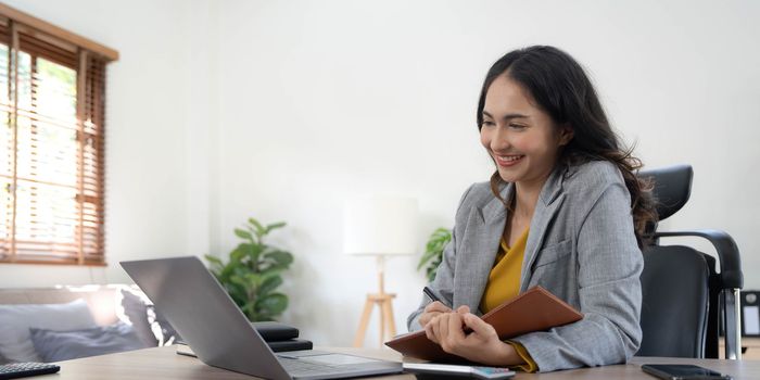 Portrait of an Asian young business Female working on a laptop computer in her workstation.Business people employee freelance online report marketing concept