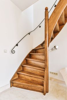 White hallway with wooden stairway leading to second floor of modern luxury apartment with minimalist interior design