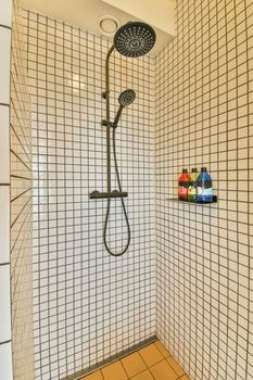 Tile partition between shower tap and wall hung toilet in modern restroom at home