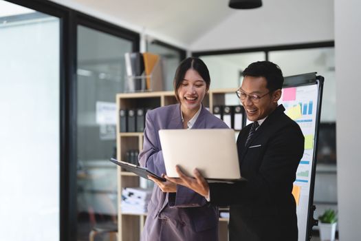 business people meet and discuss chart and point at chart Company report share marketing in the office. Business team stand to discuss and work together at the office.