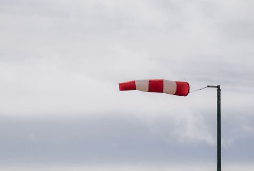 Frayed windsock in moderate wind against blue sky with copy space