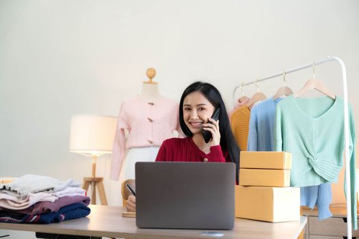 Portrait of Starting small businesses SME owners, Asian woman check online orders Selling products working with boxs freelance work at home office, sme business online small medium enterprise..