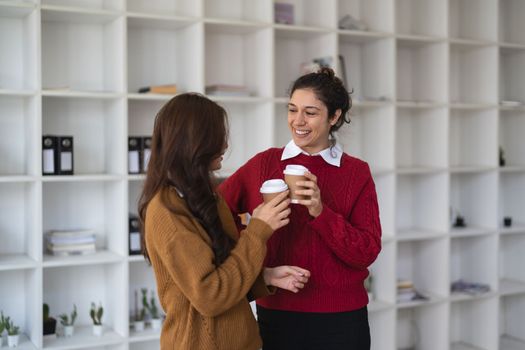 Diverse friendly coworkers coffee break talking office. Caucasian manager having discussion with asian employee meeting in office lobby discussing project, teaching new employee sharing ideas