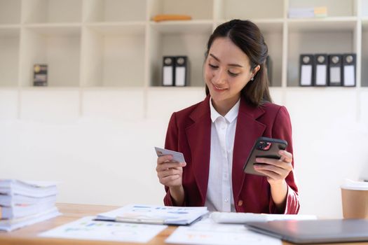 Happy asian Business woman pay online using mobile phone at the office