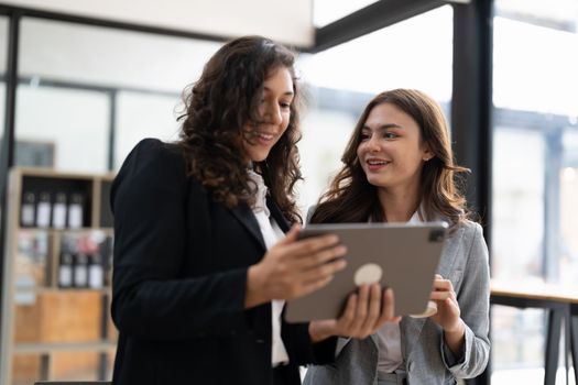 Diverse businesspeople cooperate work together discussing company financial statistics, multiracial colleagues collaborate brainstorm with finance on tablet