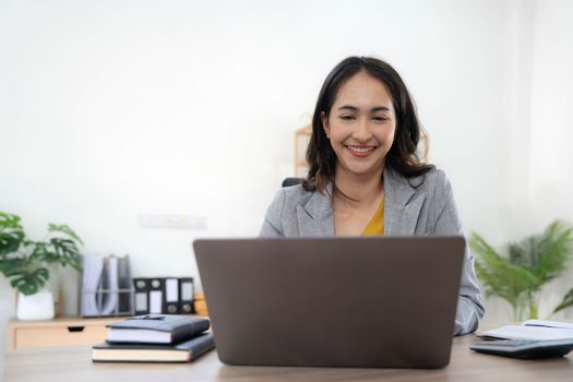 Portrait of an Asian young business Female working on a laptop computer in her workstation.Business people employee freelance online report marketing concept