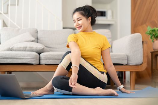 Attractive young woman doing yoga stretching yoga online at home. Self-isolation is beneficial, entertainment and education on the Internet. Healthy lifestyle concept.