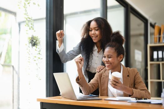 Excited african women achieving goals excited raised hands rejoicing with laptop in the office. New startup project concept