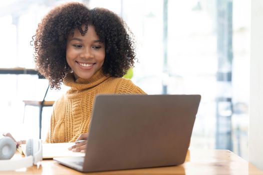 Photo of cheerful joyful woman in yellow shirt smiling work on laptop talk speak video call online. Smart ethnic female in earphones study distant on computer at home. Education concept...