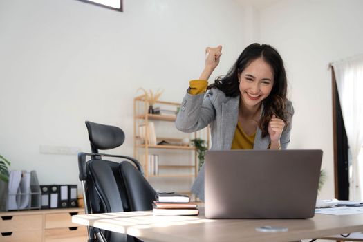 Happy excited asian woman celebrate with computer laptop, success or happy action. Freelancer or Entrepreneur using technology and start up modern home