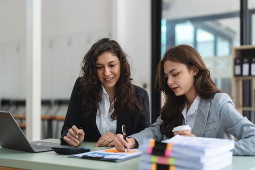 Diverse businesspeople cooperate work together discussing company financial statistics, multiracial colleagues collaborate brainstorm with finance on tablet