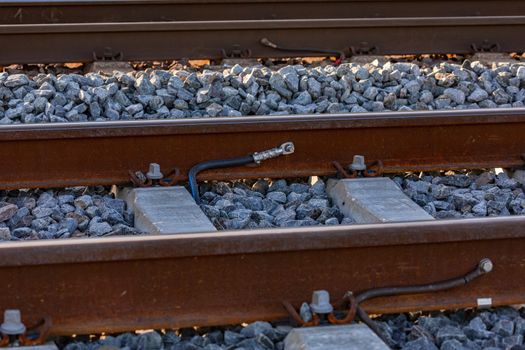 Cable lugs on a rail on a railroad track in a ballast bed