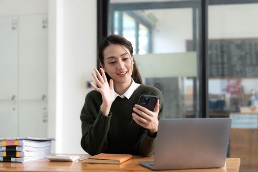 Asian businesswoman in formal suit in office happy and cheerful during using smartphone and working.