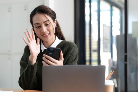 Asian businesswoman in formal suit in office happy and cheerful during using smartphone and working.