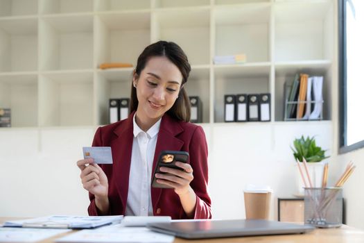 Happy asian Business woman pay online using mobile phone at the office