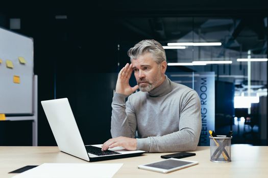 Senior thinking businessman working inside office with laptops, man thinking about important financial decision.