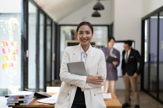 Portrait of young attractive asian female office worker in formal business suits smiling at camera in office