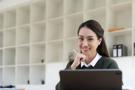 Portrait of an Asian young business Female working on a laptop computer in her workstation.Business people employee freelance online report marketing e-commerce telemarketing concept