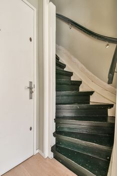 White hallway with wooden stairway leading to second floor of modern luxury apartment with minimalist interior design