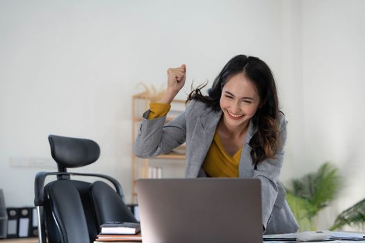 Happy excited asian woman celebrate with computer laptop, success or happy action. Freelancer or Entrepreneur using technology and start up modern home