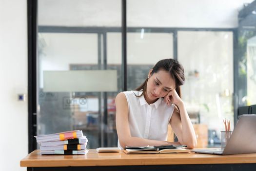 Young Business Asian women are stressed while working on laptop, Tired asian businesswoman with headache at office, feeling sick at work copy space in workplace an home office..