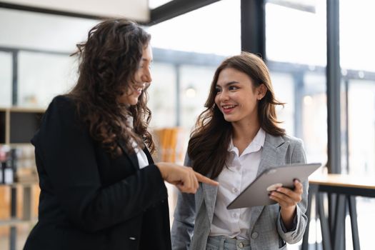 Diverse businesspeople cooperate work together discussing company financial statistics, multiracial colleagues collaborate brainstorm with finance on tablet