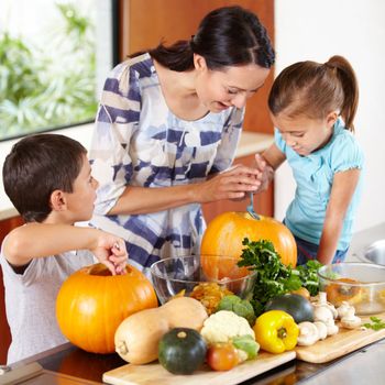 I think its ready. a mother helping her children carve pumpkins for halloween