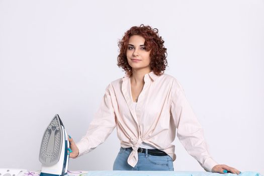 A girl with curly hair and a gentle smile on her face ready to start the daily ritual of ironing shirts. Natural hairstyle.