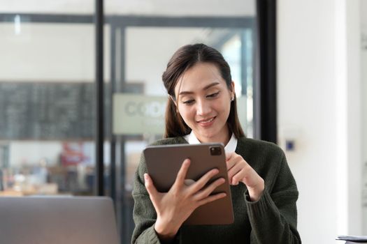 Asian Business woman using calculator and laptop for doing math finance on an office desk, tax, report, accounting, statistics, and analytical research concept.