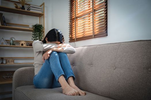 Young lonely attractive asian woman crying on couch feeling sad tired and worried suffering depression isolated at home. Mental Health and lockdown, stress, unemployment and heartbroken concept