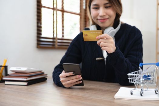 Asian girl making online payment using mobile phone for shopping at home