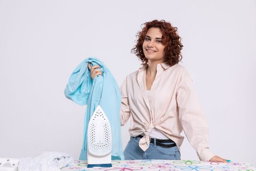 Satisfied young girl before starting ironing with iron. The girl likes to iron shirts. Daily chores at home.