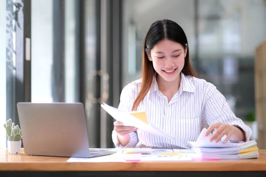 Business Documents concept : Employee woman hands working in Stacks paper files for searching and checking unfinished document achieves on folders papers at busy work desk office. Soft focus.