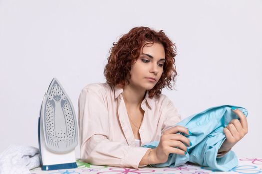 Before ironing, the girl checks the shirt to see if it is thoroughly washed. She inspects whether the shirt has any damage.