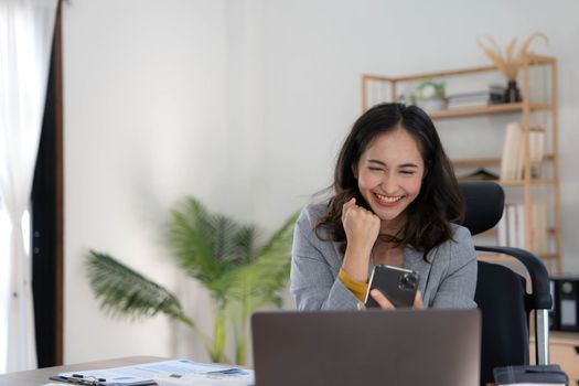 Happy excited asian woman celebrate with computer laptop, success or happy action. Freelancer or Entrepreneur using technology and start up modern home