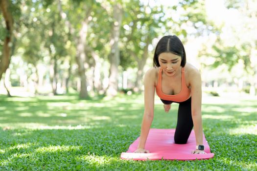 Young attractive girl is doing advanced yoga asana on the fitness mat in the middle of a park