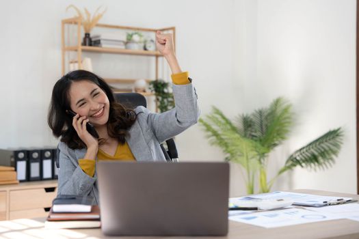 Happy excited asian woman celebrate with computer laptop, success or happy action. Freelancer or Entrepreneur using technology and start up modern home