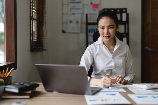 Woman accountant using calculator and laptop computer in office, finance and accounting concept.