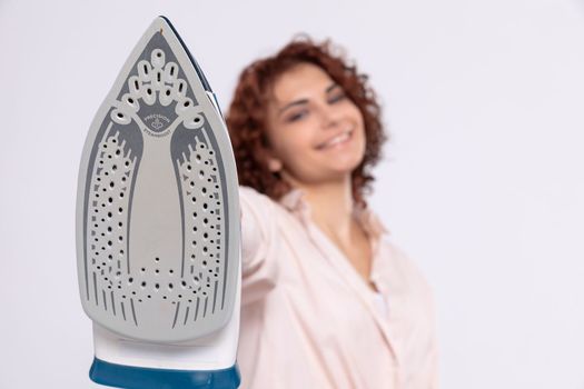 The foot of a household iron. Close-up view. A girl prepared to do housework. Readiness to iron. A hand drawn up over itself.